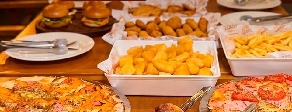 Mesa do rodízio com pizzas, mini hambúrgueres e porções